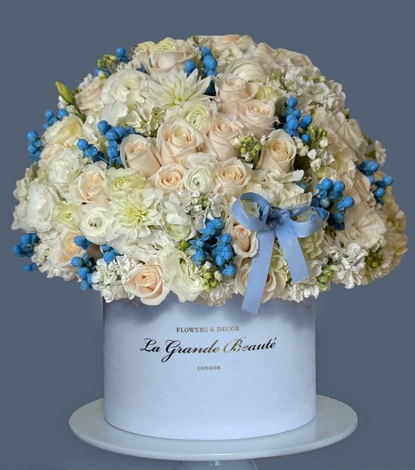The arrangement in the photo includes white roses, ranunculus, eustomas and hypericum berries is in our exquisite, white velvet 26cm La Grande Beaute box.
