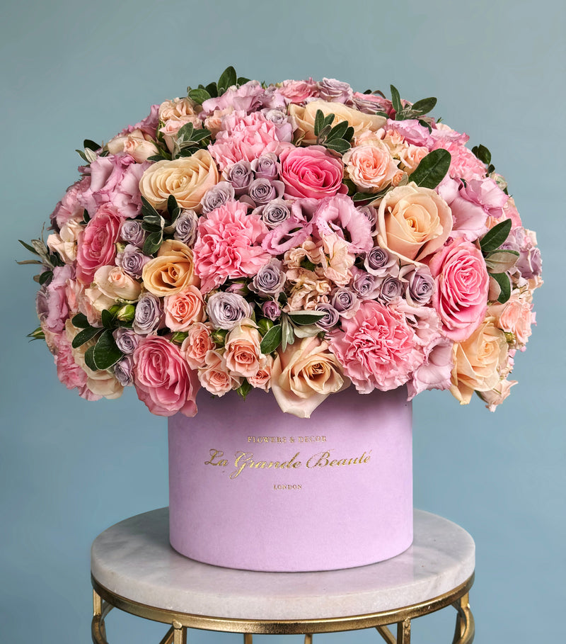 This photograph shows our 'Blooming Pink' box, a mix of pink garden roses, spray roses, ranunculi, carnations, and eustomas in a 23cm Lilac 'La Grande Beauté' box
