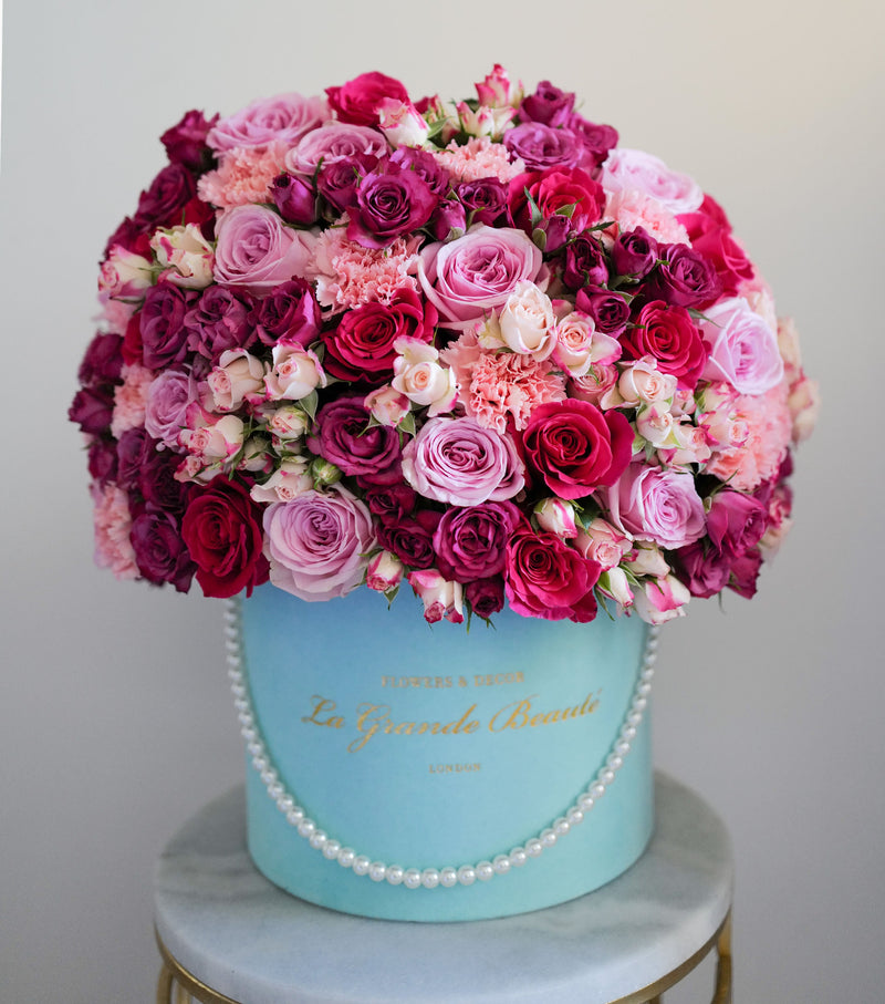 ''XOXO'' this stunning box of classic blush and hot pink roses, spray roses and carnations. The arrangement in the photo is in the blue 25cm "La Grande Beaute" velvet box decorated with white pearl string. Luxury London delivery