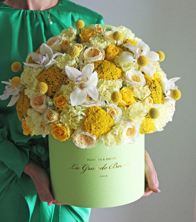 This box is a mix of fresh yellow roses, carnations and orchids. Placed in a large green La Grande Beaute box 